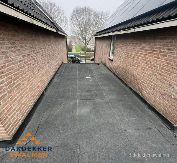 Plat dak met bitumen dakbedekking tussen bakstenen muren in Swalmen Plat dak met bitumen dakbedekking tussen bakstenen muren in Swalmen