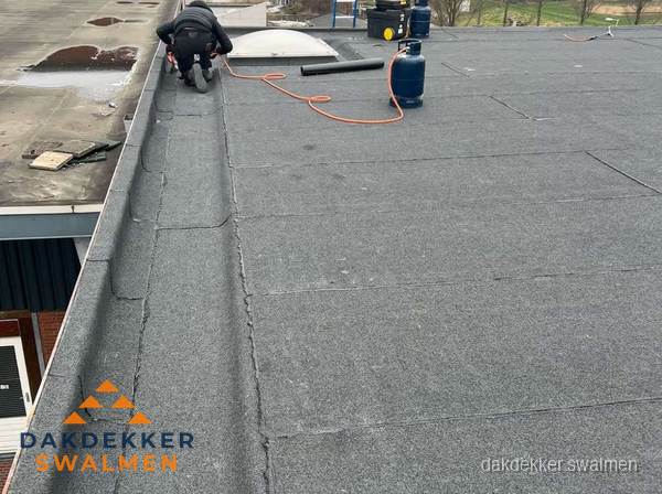 Dakdekker repareert bitumen dakbedekking op groot plat dak in Swalmen